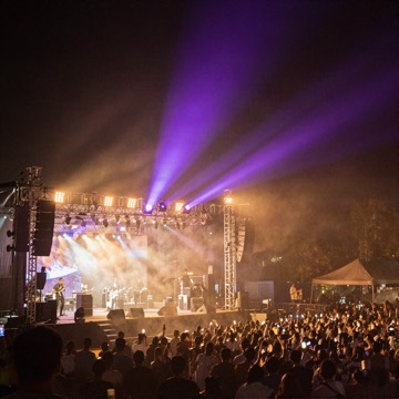 Outdoor concert stage at night with purple and gold lights