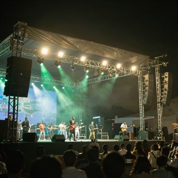 Open-air concert stage at night with green and white lights