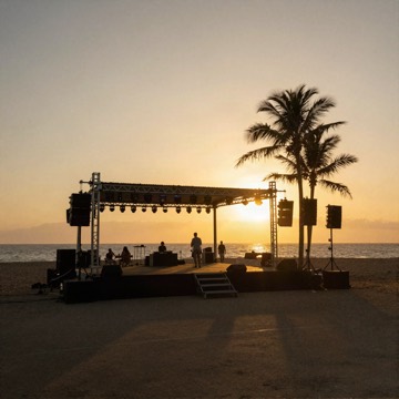 Beach stage with speakers and palm trees at sunset
