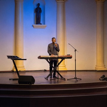 Worship stage with a keyboard and microphones under blue and gold lights