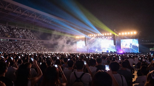 Stadium crowd with phone lights and colourful stage lights