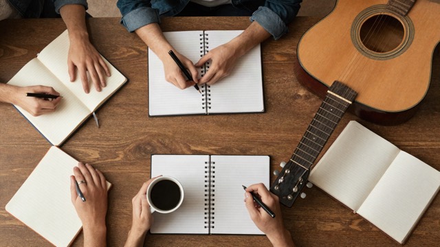 Top-down view of a songwriting session with notebooks and a guitar